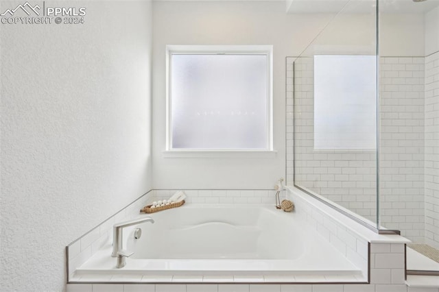 bathroom featuring plus walk in shower and a wealth of natural light