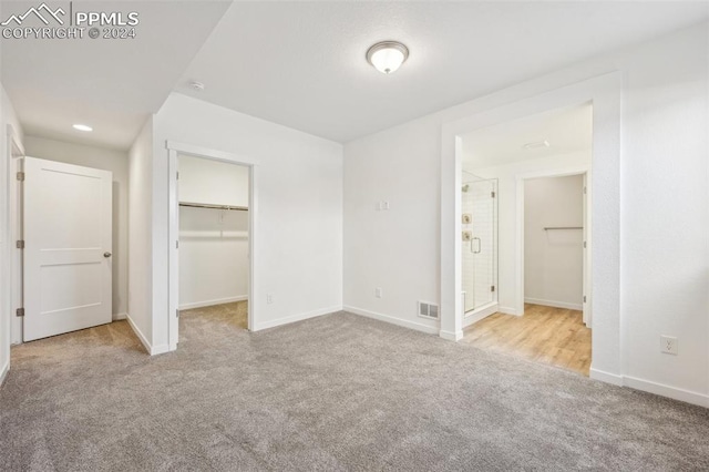 unfurnished bedroom featuring light carpet, a spacious closet, and a closet