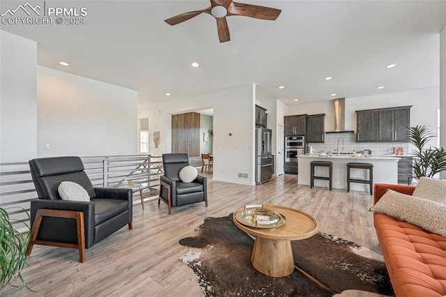 living room featuring ceiling fan, light hardwood / wood-style flooring, and sink