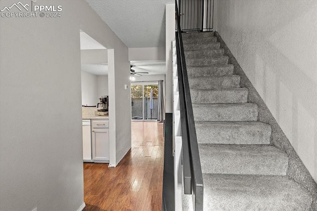 staircase with hardwood / wood-style floors and ceiling fan