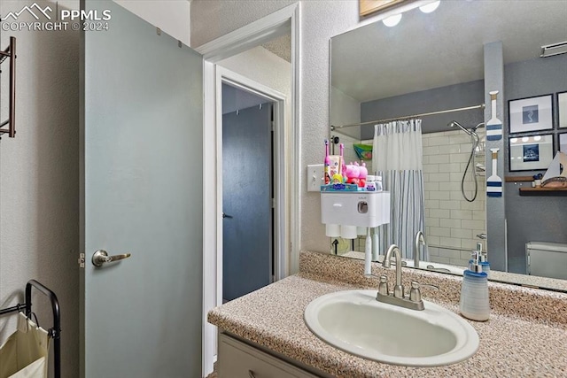 bathroom featuring a shower with shower curtain, vanity, and toilet