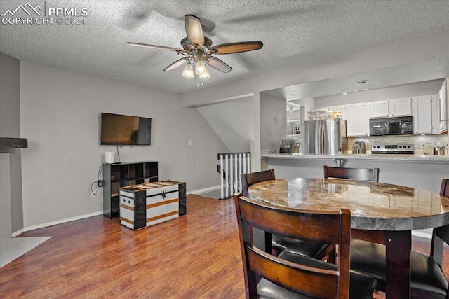 dining area with lofted ceiling, ceiling fan, light hardwood / wood-style floors, and a textured ceiling