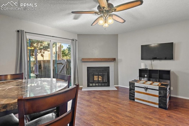 living room featuring ceiling fan, a fireplace, dark wood-type flooring, and a textured ceiling