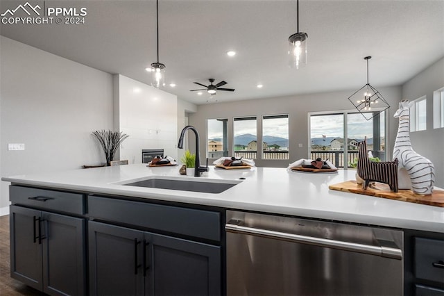 kitchen featuring dishwasher, sink, dark hardwood / wood-style flooring, pendant lighting, and ceiling fan with notable chandelier