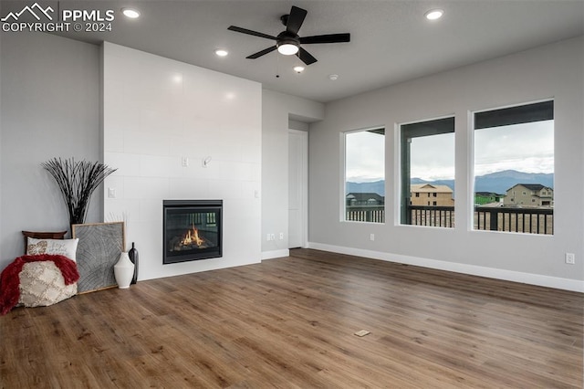 unfurnished living room with ceiling fan, a fireplace, and wood-type flooring