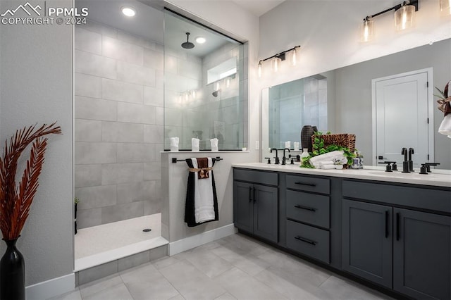 bathroom with tile patterned flooring, vanity, and tiled shower