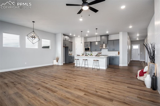 unfurnished living room with ceiling fan with notable chandelier, sink, and dark wood-type flooring