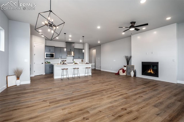 kitchen with a kitchen breakfast bar, gray cabinets, dark hardwood / wood-style floors, and an island with sink