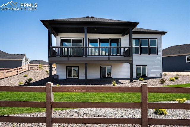 rear view of house featuring a lawn and a balcony