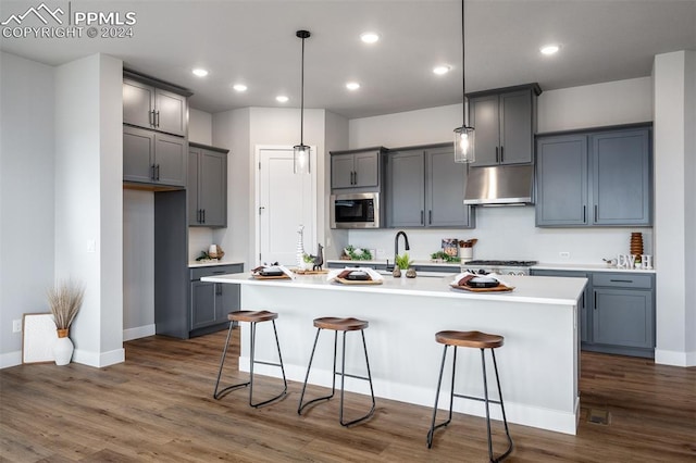 kitchen with a kitchen breakfast bar, decorative light fixtures, an island with sink, and appliances with stainless steel finishes