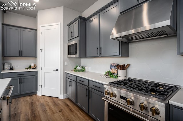 kitchen with tasteful backsplash, gray cabinetry, dark hardwood / wood-style floors, and appliances with stainless steel finishes