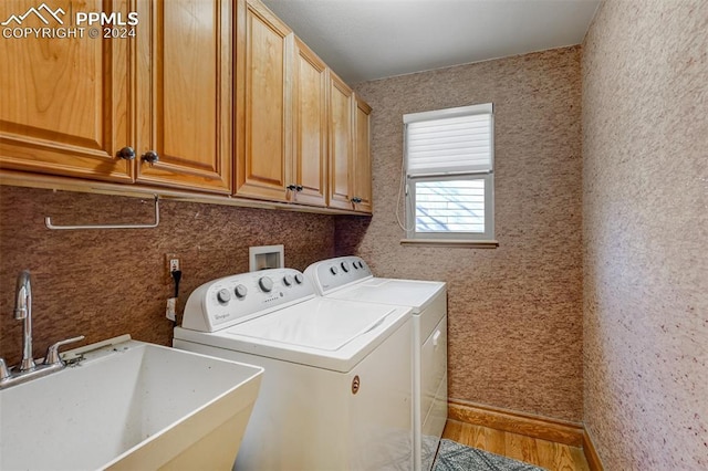 washroom featuring cabinets, wood-type flooring, sink, and washing machine and clothes dryer