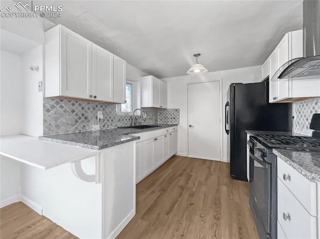 kitchen featuring white cabinets, stainless steel range with gas cooktop, sink, wall chimney exhaust hood, and light wood-type flooring