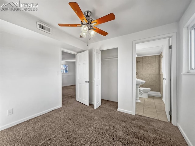 unfurnished bedroom with carpet, ceiling fan, connected bathroom, and a closet