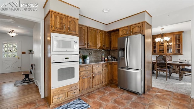 kitchen featuring tasteful backsplash, white appliances, a chandelier, carpet floors, and hanging light fixtures