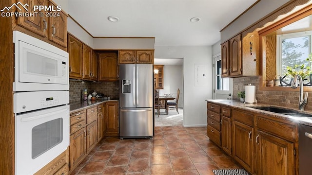 kitchen with backsplash, sink, dark tile patterned flooring, and appliances with stainless steel finishes