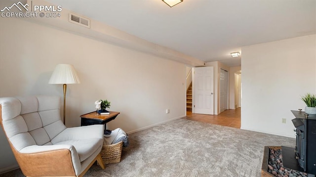 living area featuring a wood stove and light carpet