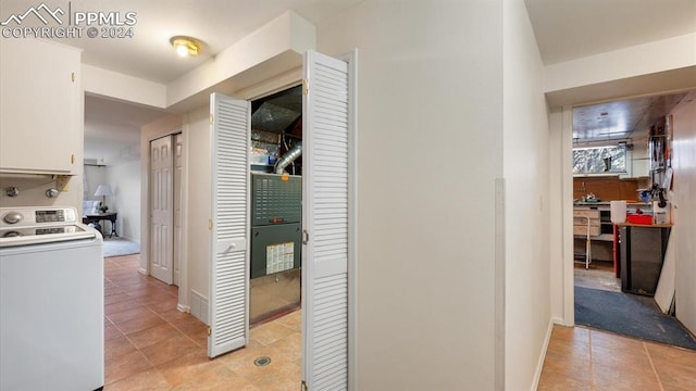 hallway featuring light tile patterned floors and washer / dryer