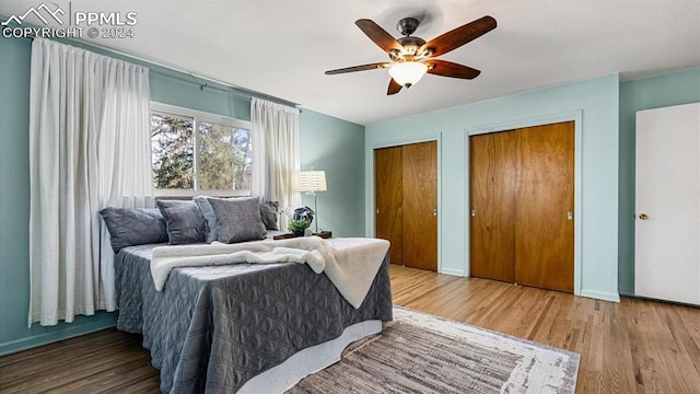 bedroom featuring two closets, hardwood / wood-style flooring, and ceiling fan