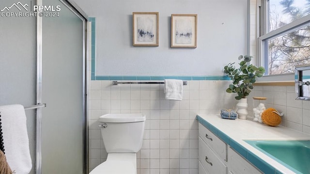 bathroom featuring walk in shower, vanity, tile walls, and toilet