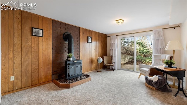 living area featuring light carpet, a wood stove, and wooden walls