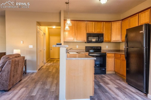 kitchen featuring black appliances, sink, hanging light fixtures, and dark wood-type flooring