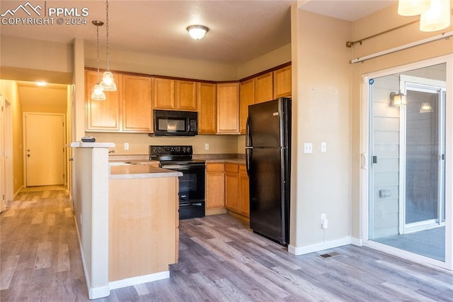 kitchen featuring decorative light fixtures, light hardwood / wood-style flooring, and black appliances