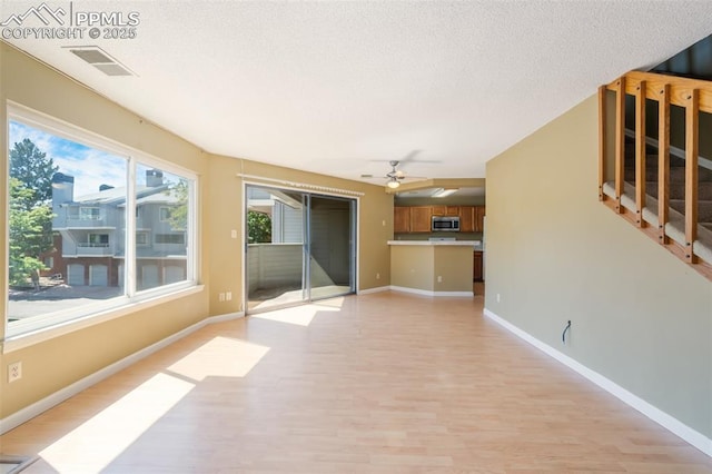 interior space with ceiling fan, light hardwood / wood-style floors, and a textured ceiling