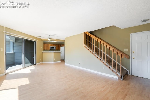 unfurnished living room featuring ceiling fan and light hardwood / wood-style flooring