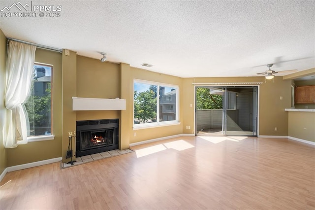 unfurnished living room with ceiling fan, light hardwood / wood-style floors, and a textured ceiling