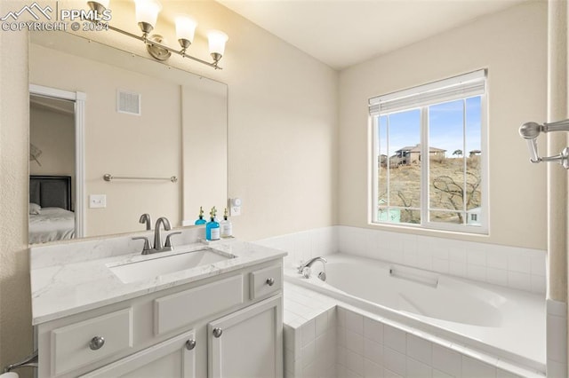 bathroom featuring vanity and a relaxing tiled tub