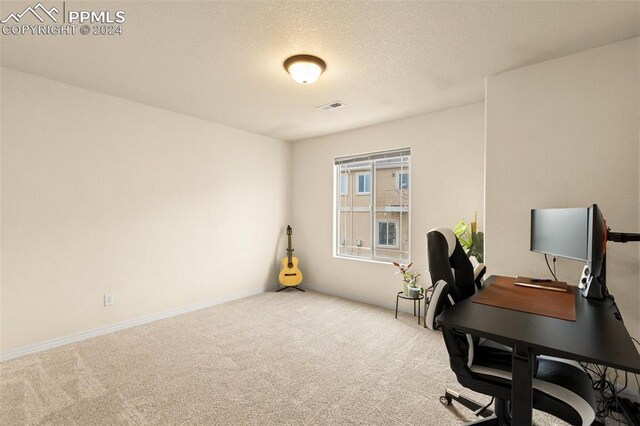 carpeted home office featuring a textured ceiling