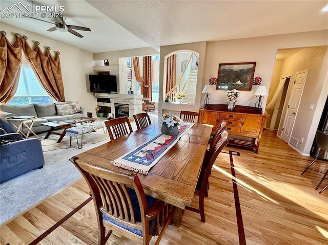 dining area featuring a fireplace, light hardwood / wood-style floors, and ceiling fan