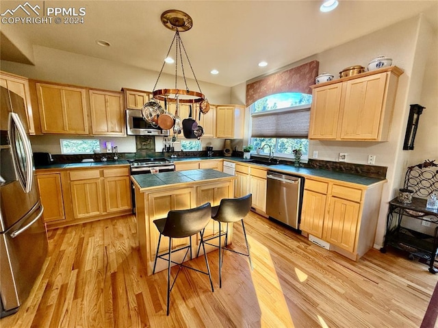 kitchen with hanging light fixtures, a breakfast bar area, light hardwood / wood-style flooring, a kitchen island, and stainless steel appliances