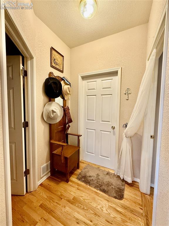 hallway featuring light hardwood / wood-style floors and a textured ceiling