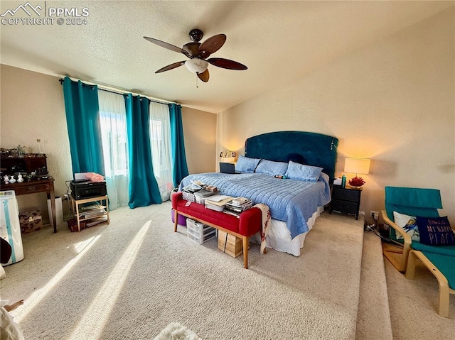 carpeted bedroom with ceiling fan and a textured ceiling