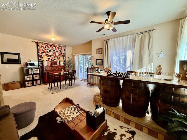 carpeted living room featuring ceiling fan and a textured ceiling