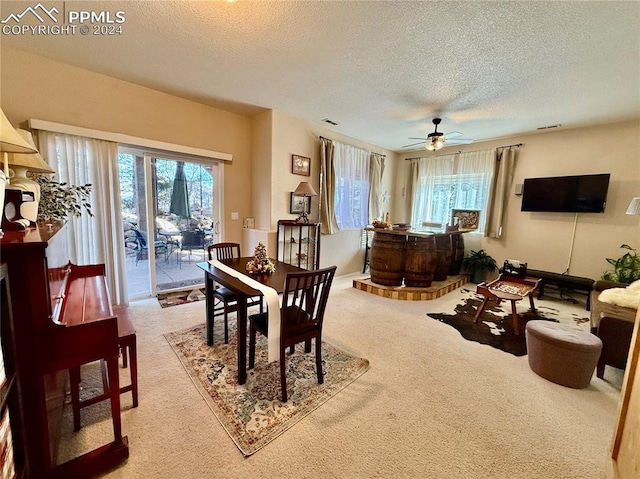 carpeted dining room featuring a textured ceiling and ceiling fan