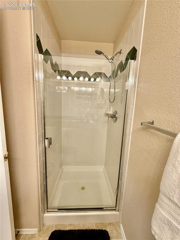 bathroom with tile patterned floors and a shower with door