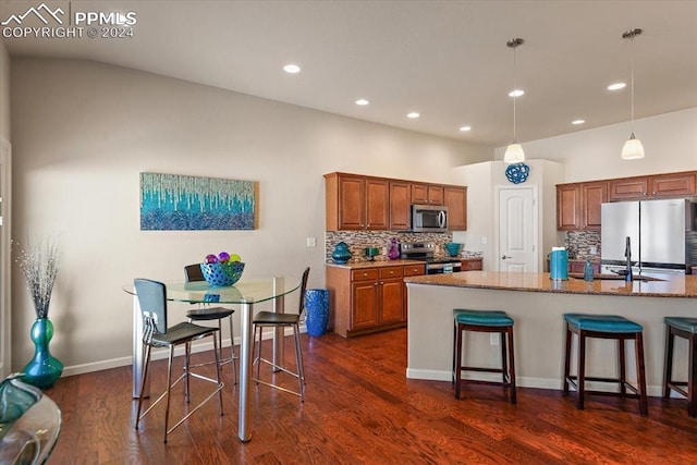 kitchen with light stone countertops, backsplash, stainless steel appliances, and dark wood-type flooring