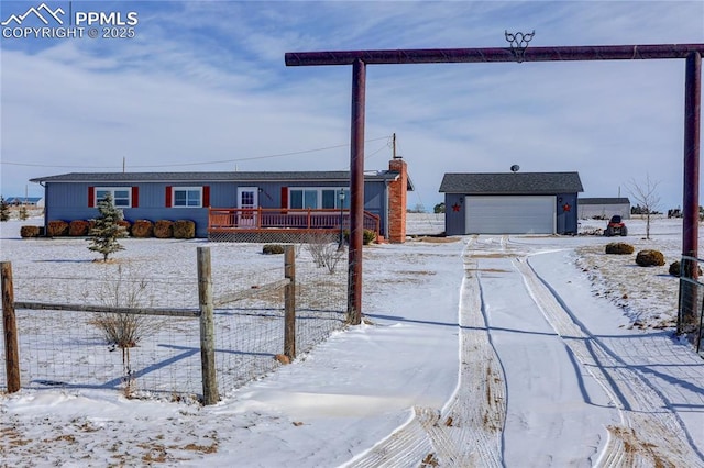 snowy yard with a garage, fence, and a deck