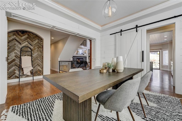 dining room featuring crown molding, a barn door, and dark hardwood / wood-style floors