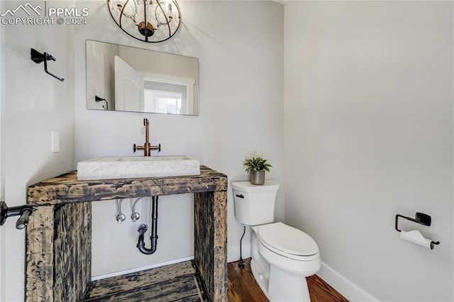 bathroom featuring toilet, wood-type flooring, a notable chandelier, and sink