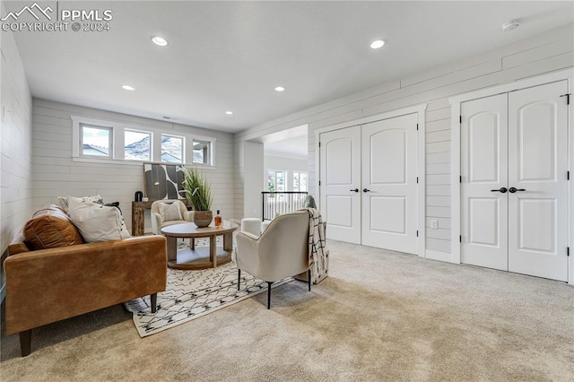 sitting room featuring light carpet and wood walls