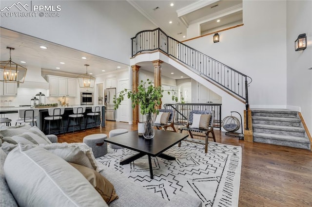 living room featuring crown molding, a towering ceiling, dark hardwood / wood-style floors, and decorative columns