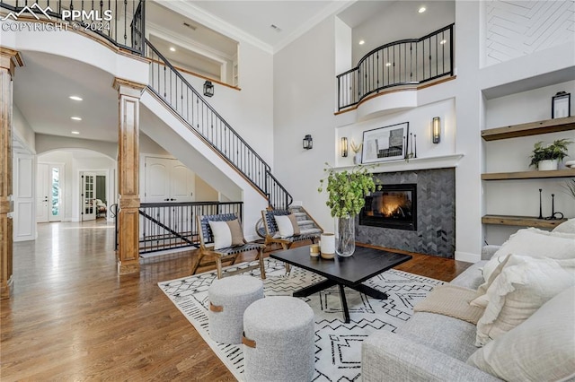 living room featuring crown molding, a fireplace, hardwood / wood-style floors, and built in shelves