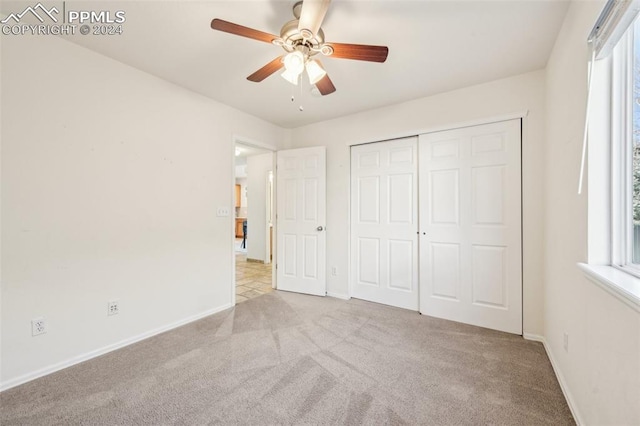 unfurnished bedroom with ceiling fan, a closet, and light carpet