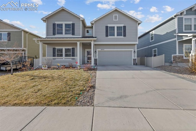 view of property featuring a porch, a garage, and a front yard