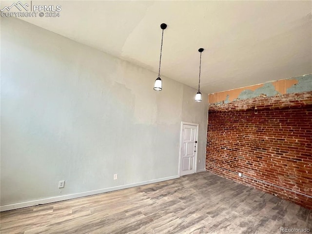 empty room featuring hardwood / wood-style floors, brick wall, and a high ceiling