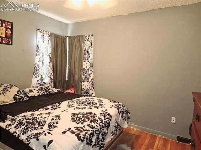 bedroom with dark hardwood / wood-style floors, ceiling fan, and a textured ceiling